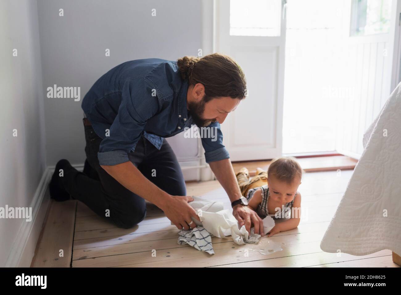 Mid adult father cleaning floor by baby boy at home Stock Photo