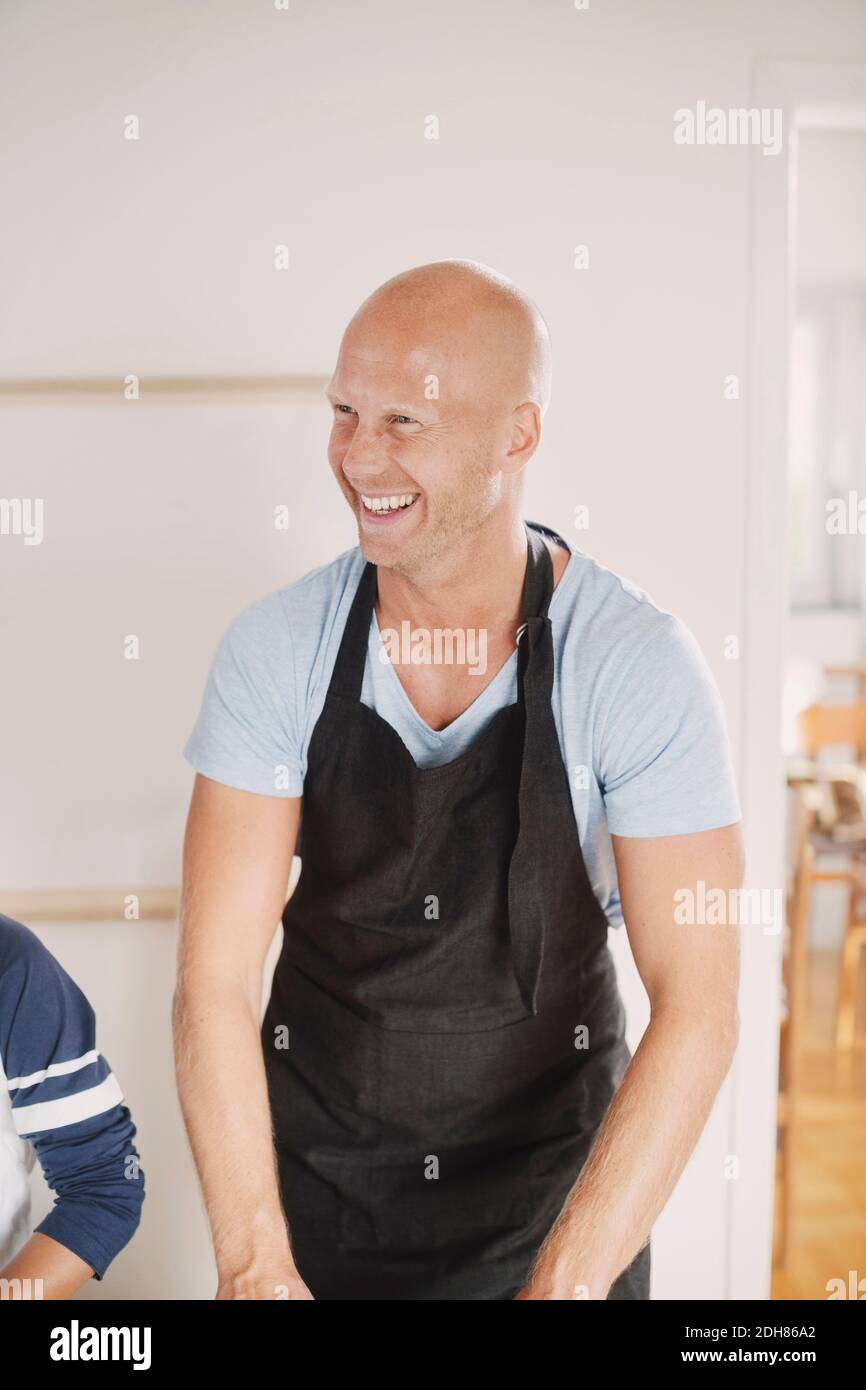 Happy man in apron looking away while standing in kitchen Stock Photo