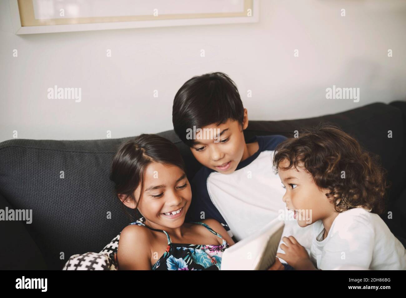 Siblings using digital tablet on sofa at home Stock Photo