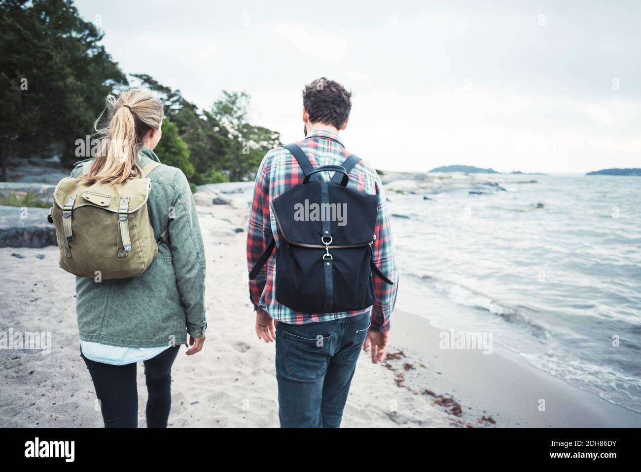Rear view of wonderlust couple walking together on beach Stock Photo