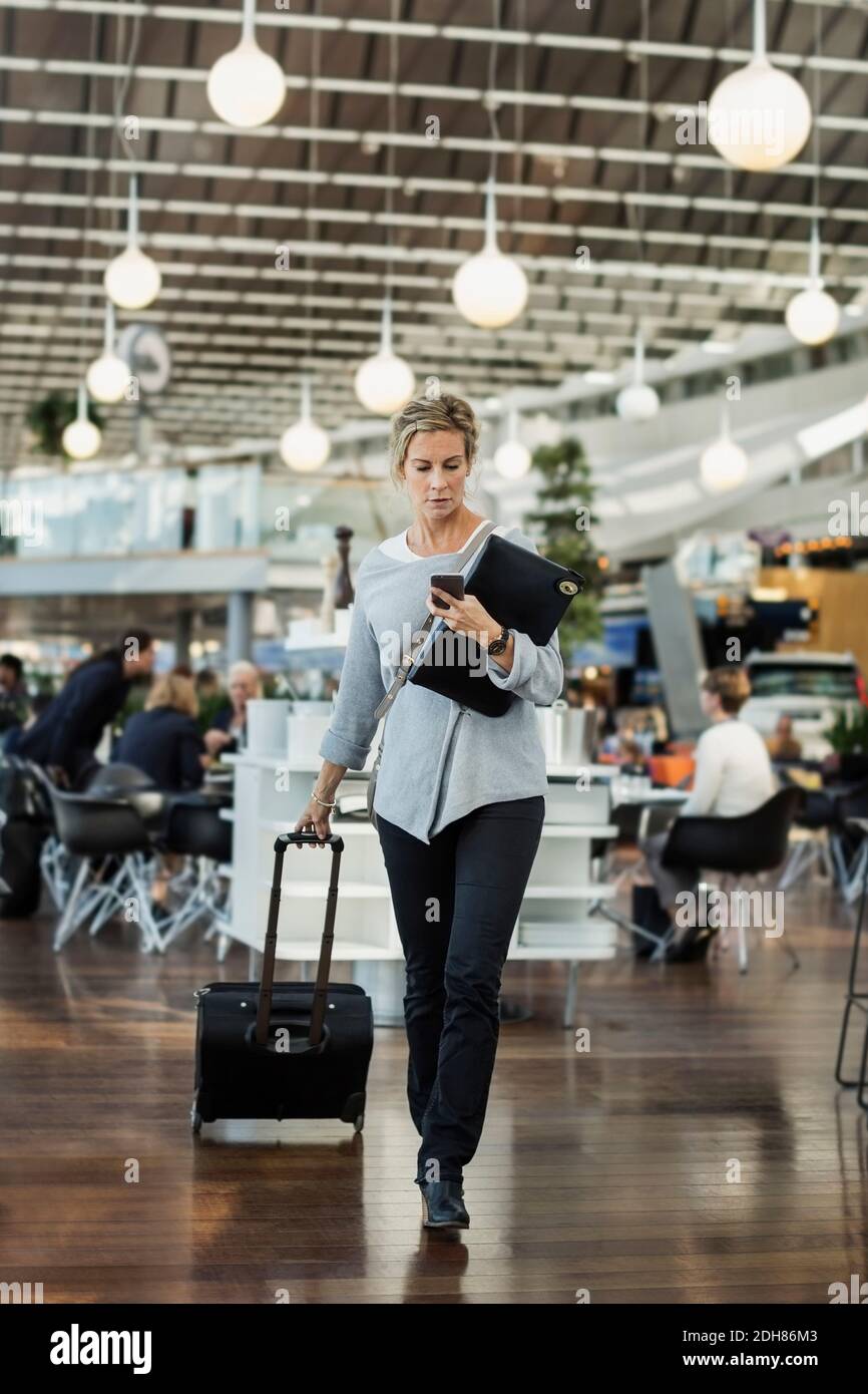 Businessman using smart phone while walking at airport Stock Photo