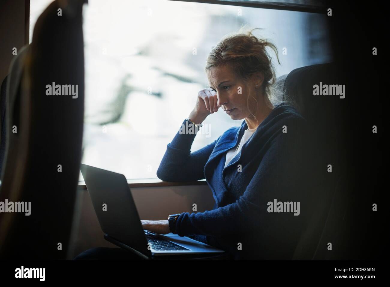 Businesswoman using laptop in train Stock Photo