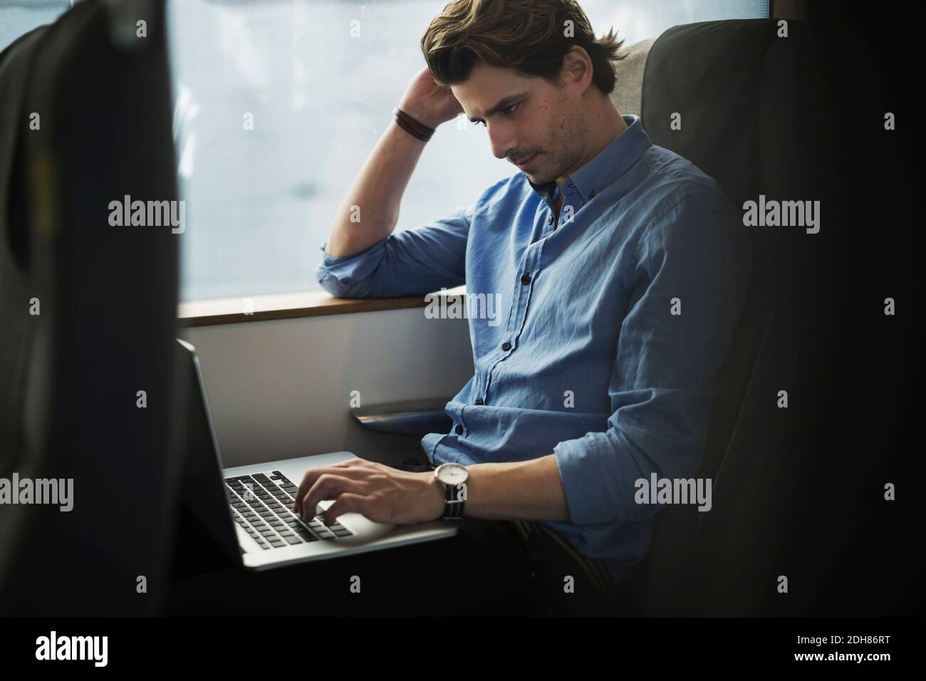 Businessman using laptop while traveling in train Stock Photo