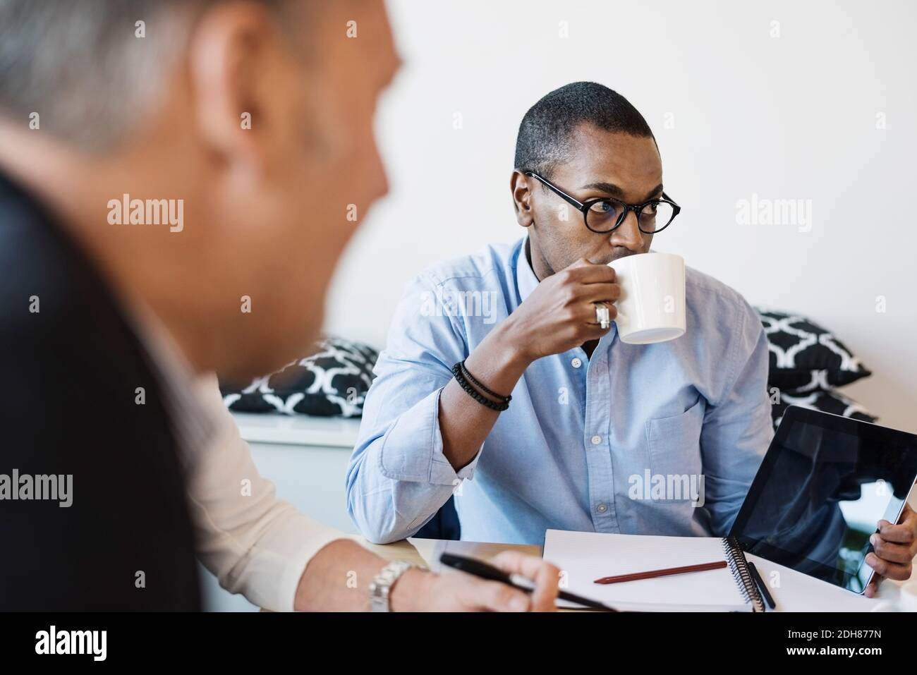 Businessman drinking coffee during meeting at office Stock Photo