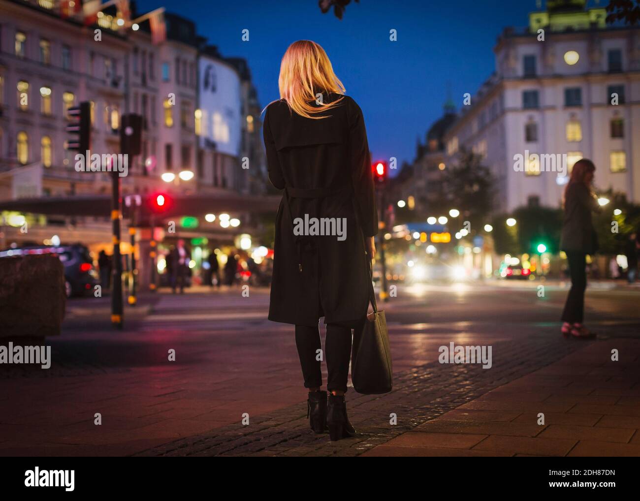 Rear view of woman walking on city street at night Stock Photo - Alamy