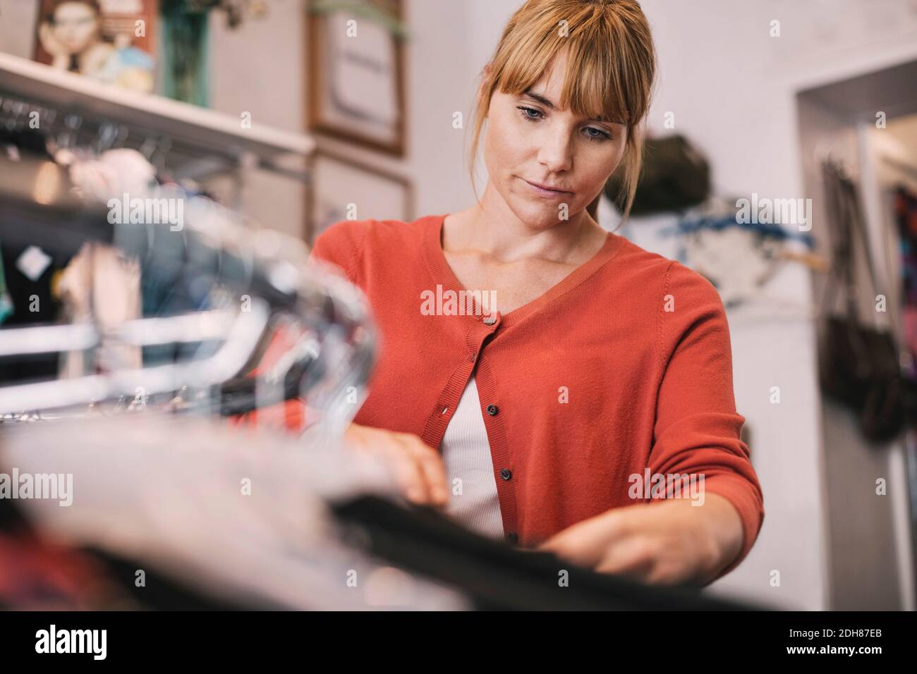 Owner arranging clothes on rack at store Stock Photo