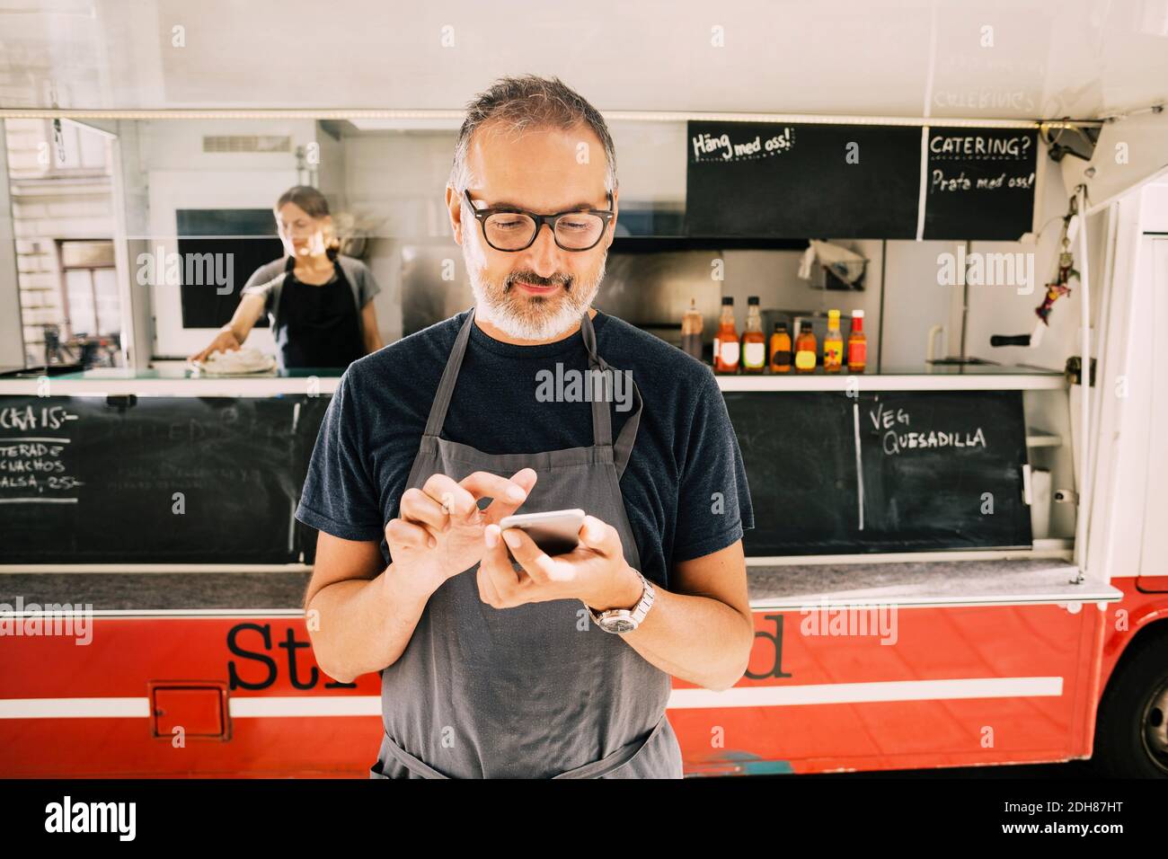Owner using mobile phone against street food truck Stock Photo