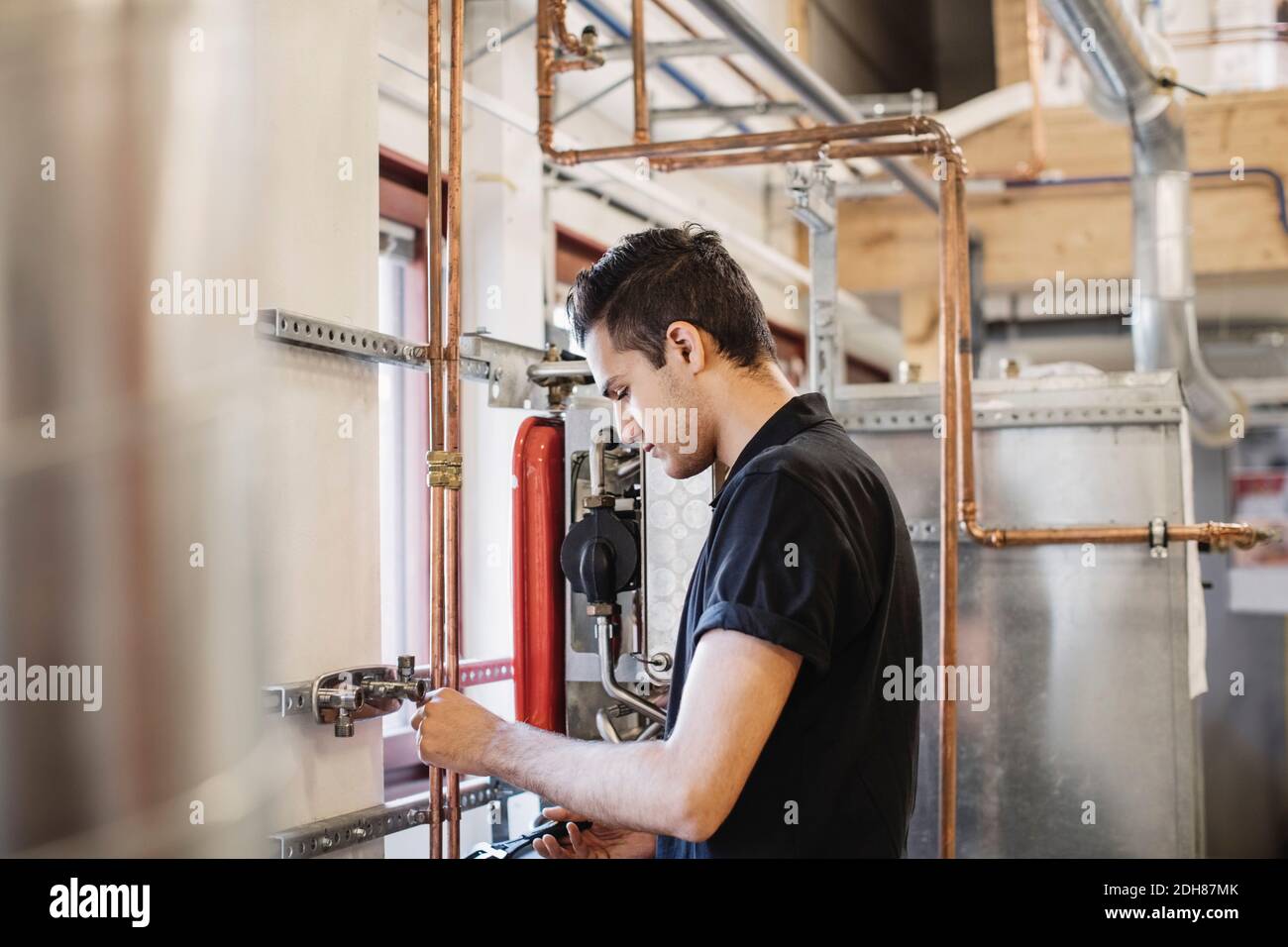 Side view of auto mechanic student analyzing machinery in workshop Stock Photo