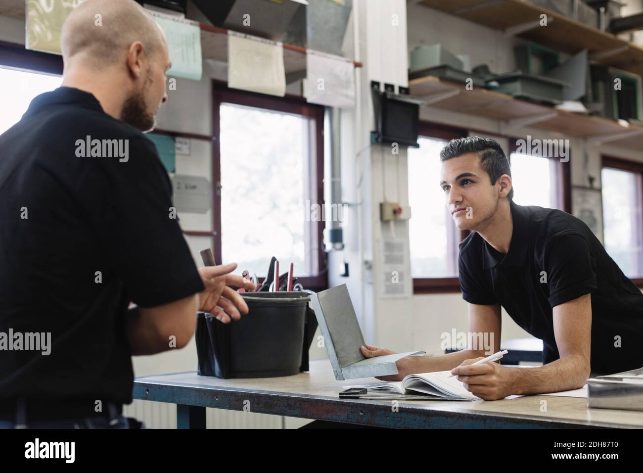 Young male teacher explaining to student in workshop Stock Photo