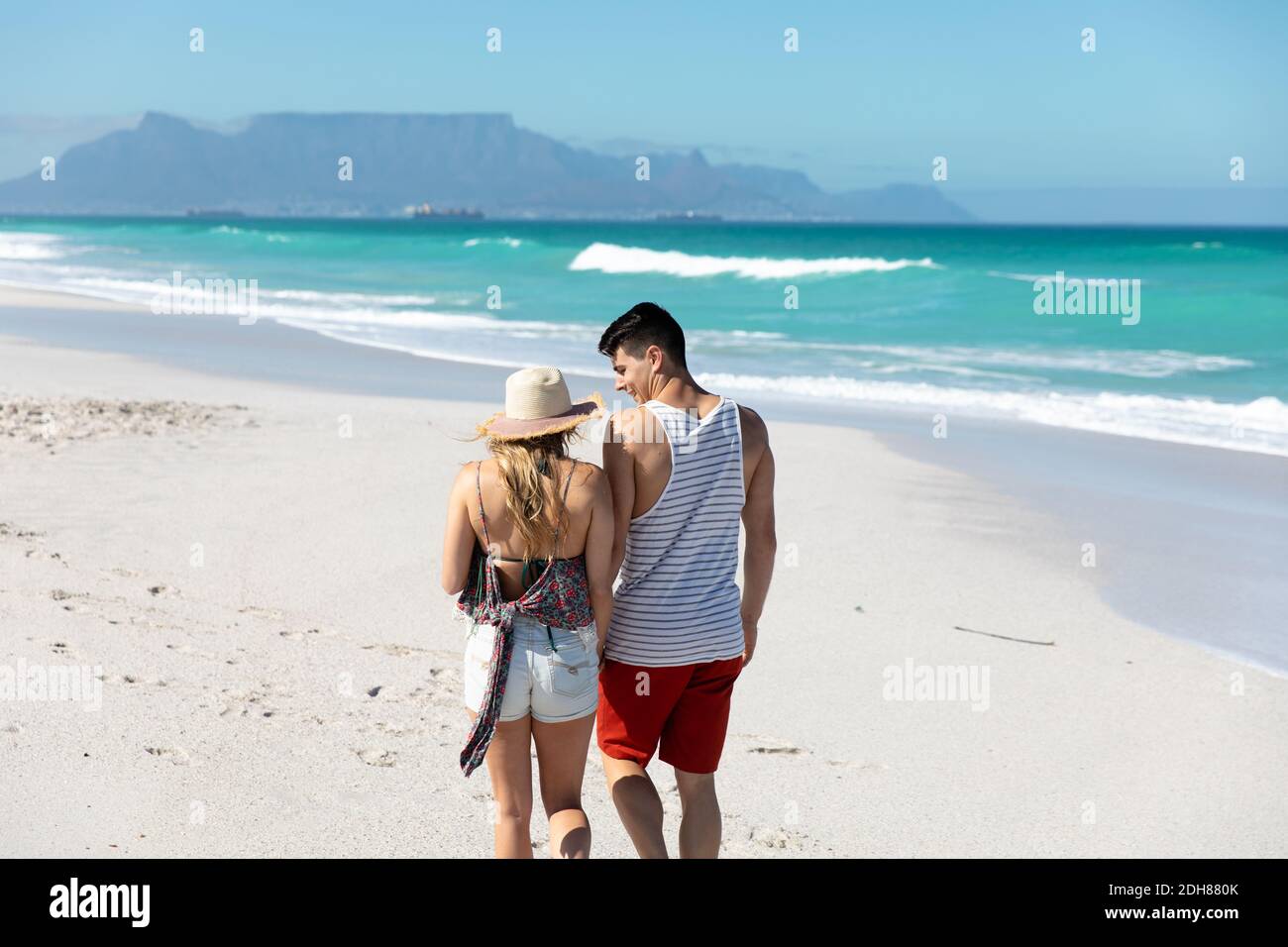 Rear view young couple walking at the beach Stock Photo - Alamy