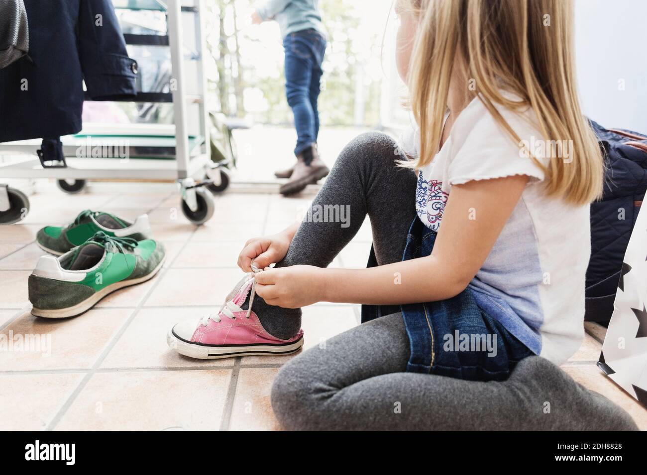 Girl wearing shoe while sitting on floor at day care center Stock Photo
