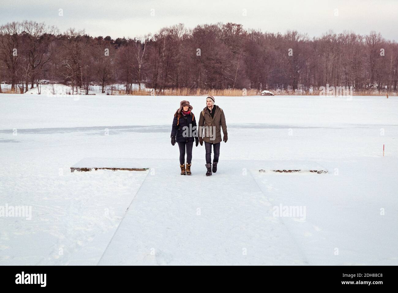 Couple walking on snow covered landscape Stock Photo