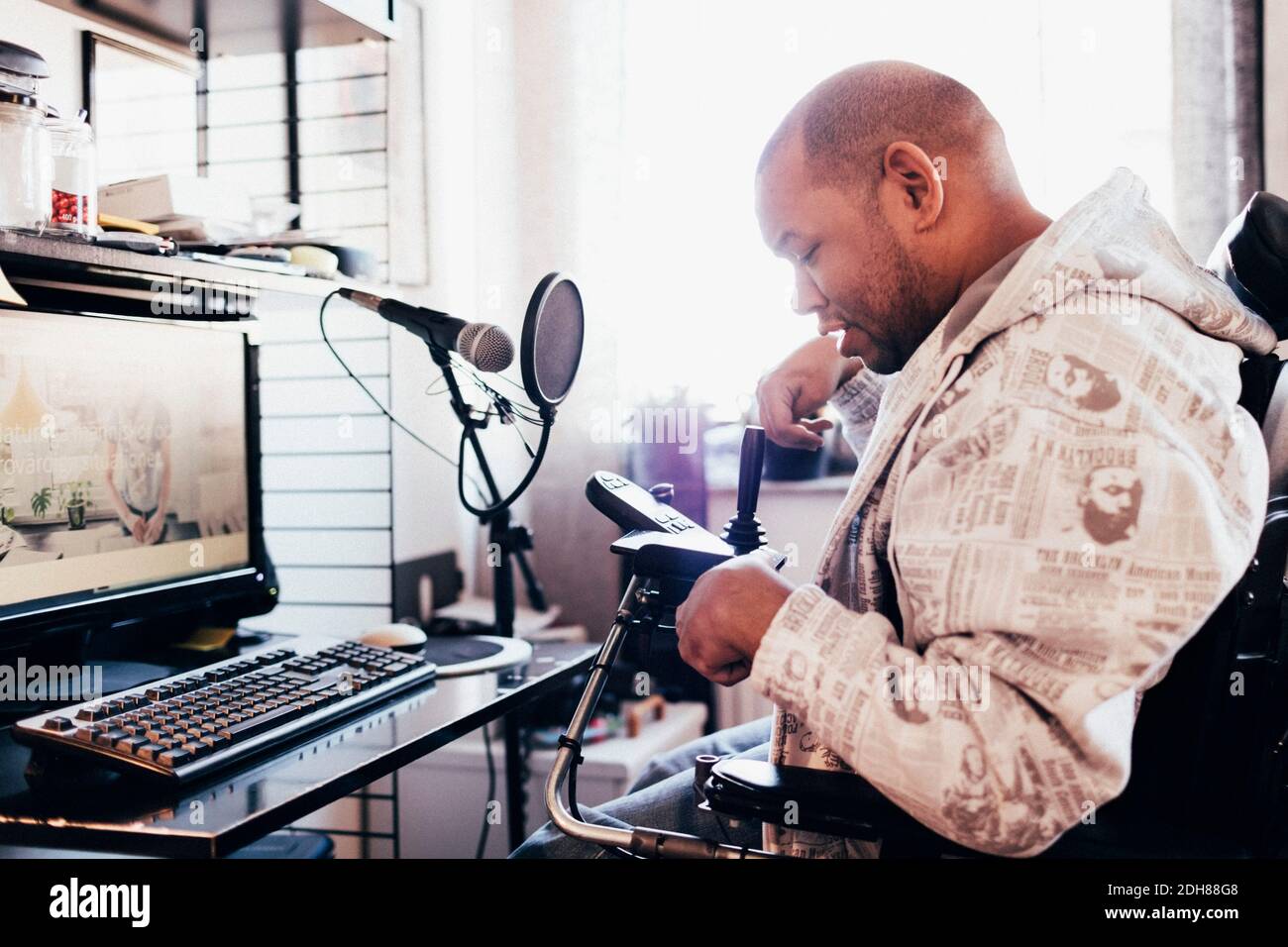 Disabled musician looking at joystick on wheelchair in recording studio
