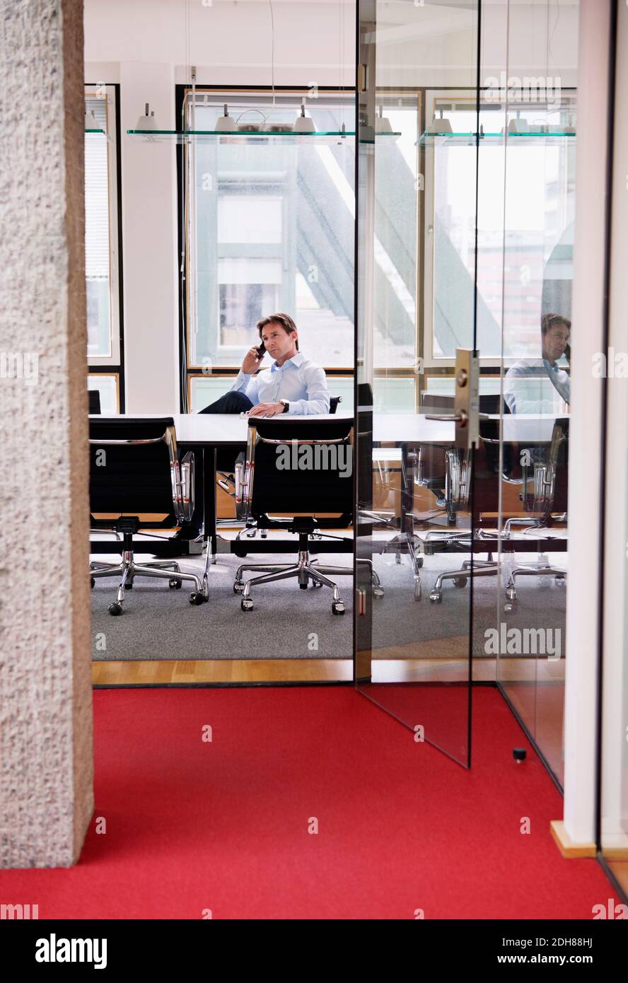 Mature businessman sitting in office talking on cell phone Stock Photo