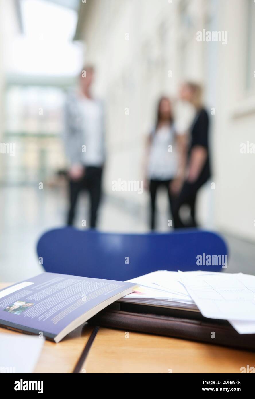 Close up of book on table with young friends standing in background Stock Photo