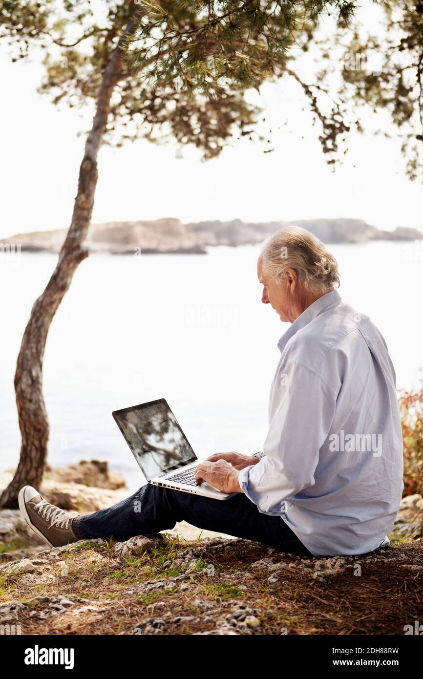 Senior man using laptop outdoors on picnic Stock Photo