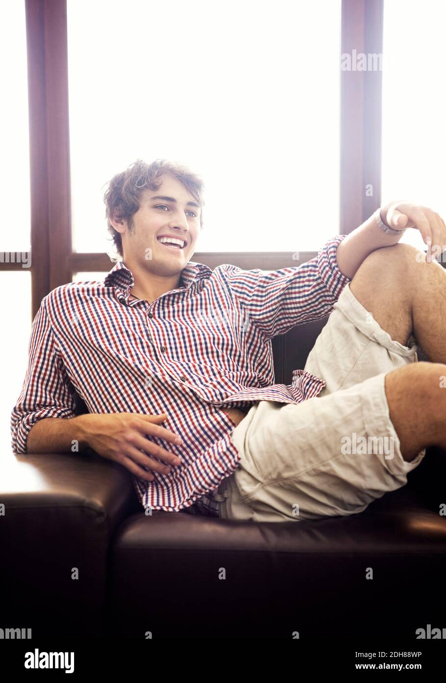 Handsome young man sitting on sofa relaxing Stock Photo