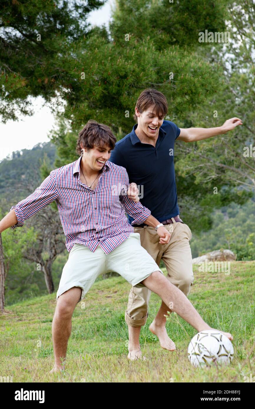 Male friends enjoying a game of soccer in park Stock Photo