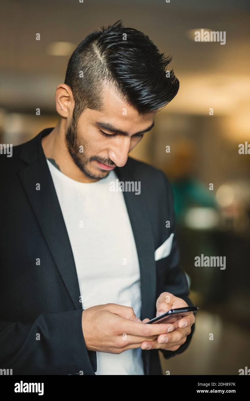 Young businessman using mobile phone in creative office Stock Photo