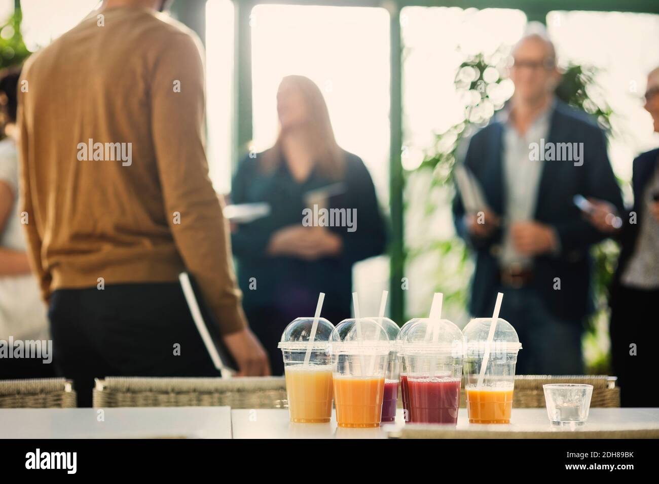 Fruit juice in plastic cups on table with business people in background at office Stock Photo