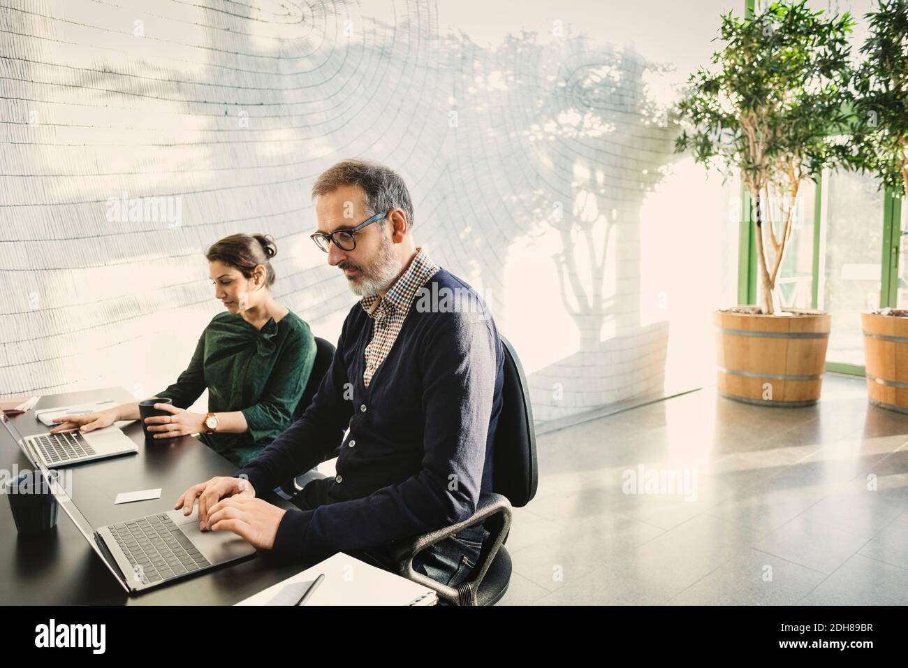 Multi-ethnic business people using laptops at table in creative office Stock Photo