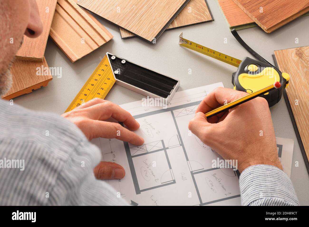 Hands on designer on desk writing on blueprints developing interior project with wood samples and tools. Elevated view. Stock Photo