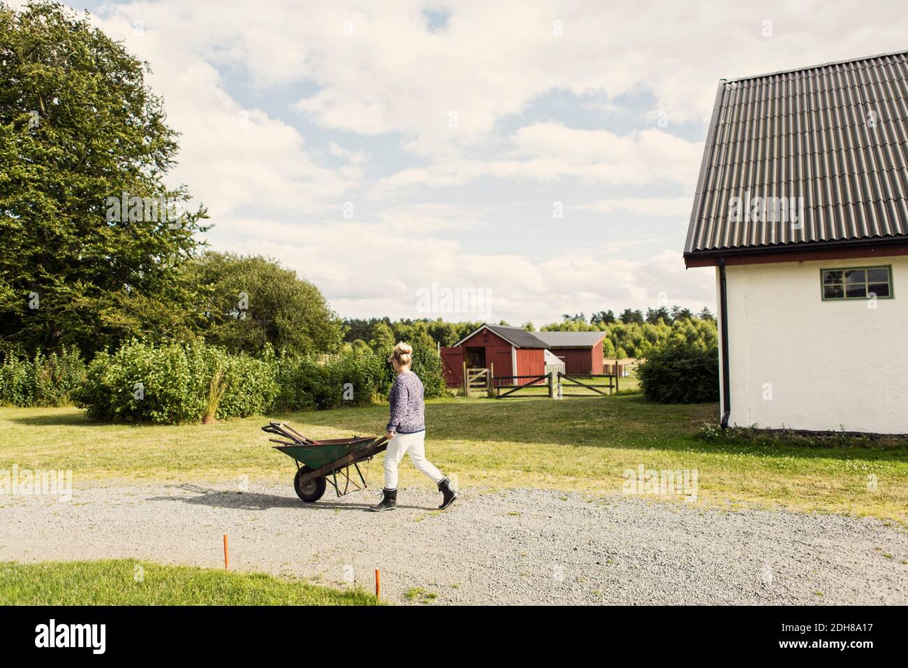 Farm worker with wheelbarrow walking on road by barn Stock Photo - Alamy