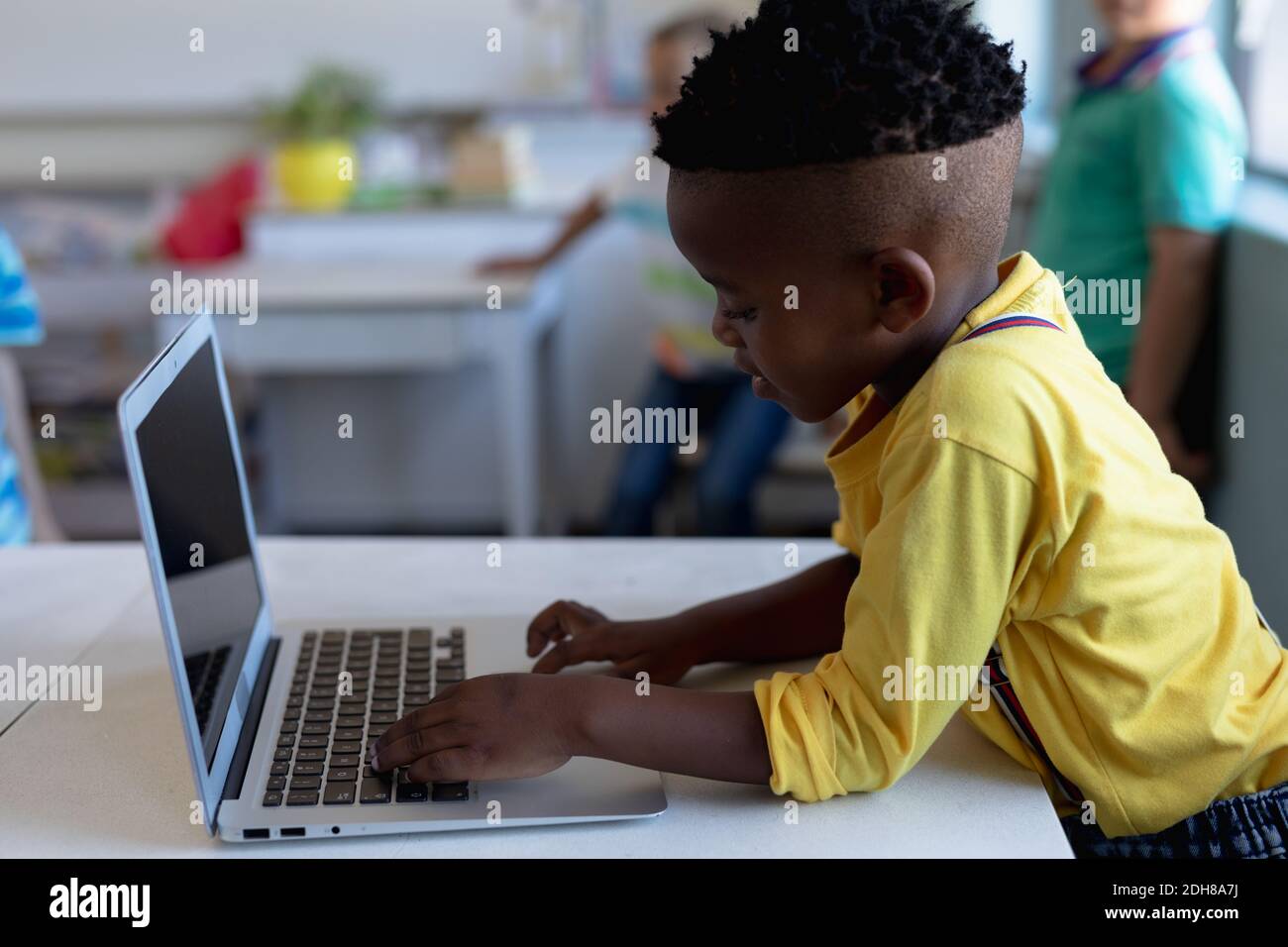 Schoolboy using a laptop computer in an elementary school classroom ...