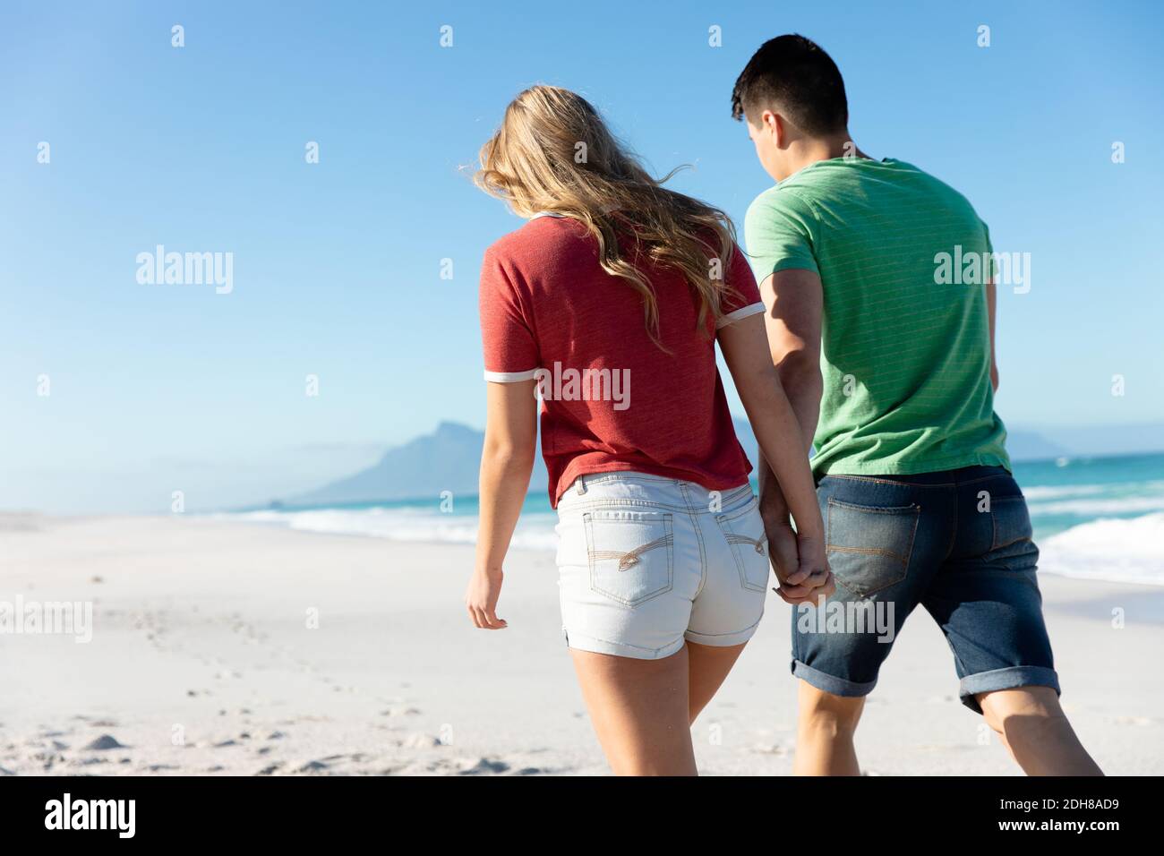Rear view young couple walking at the beach Stock Photo - Alamy