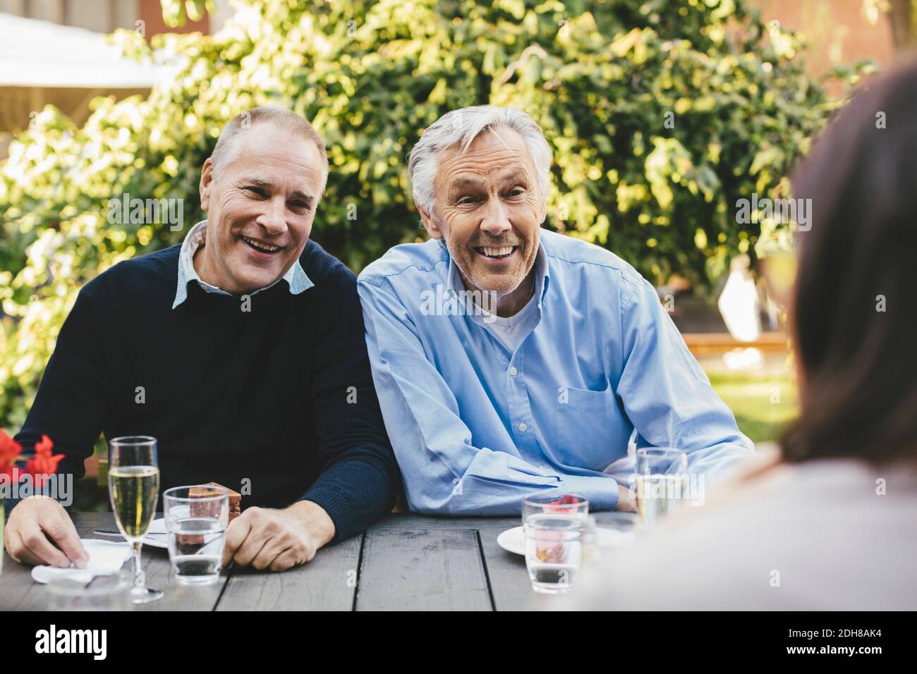 Happy senior men looking at female friend at cafe table Stock Photo