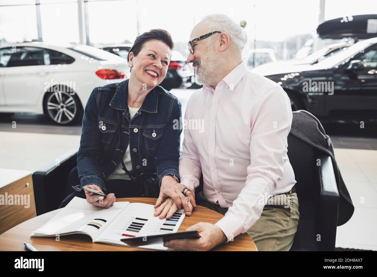 Happy senior couple reading brochure at car showroom Stock Photo
