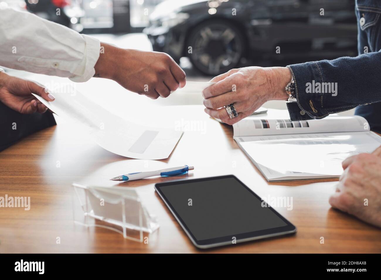 Cropped image of customer and salesperson discussing documents at showroom Stock Photo