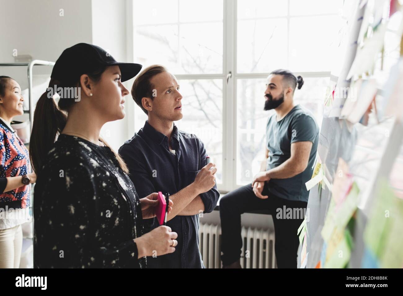 Engineers looking at whiteboard while colleagues talking in background Stock Photo