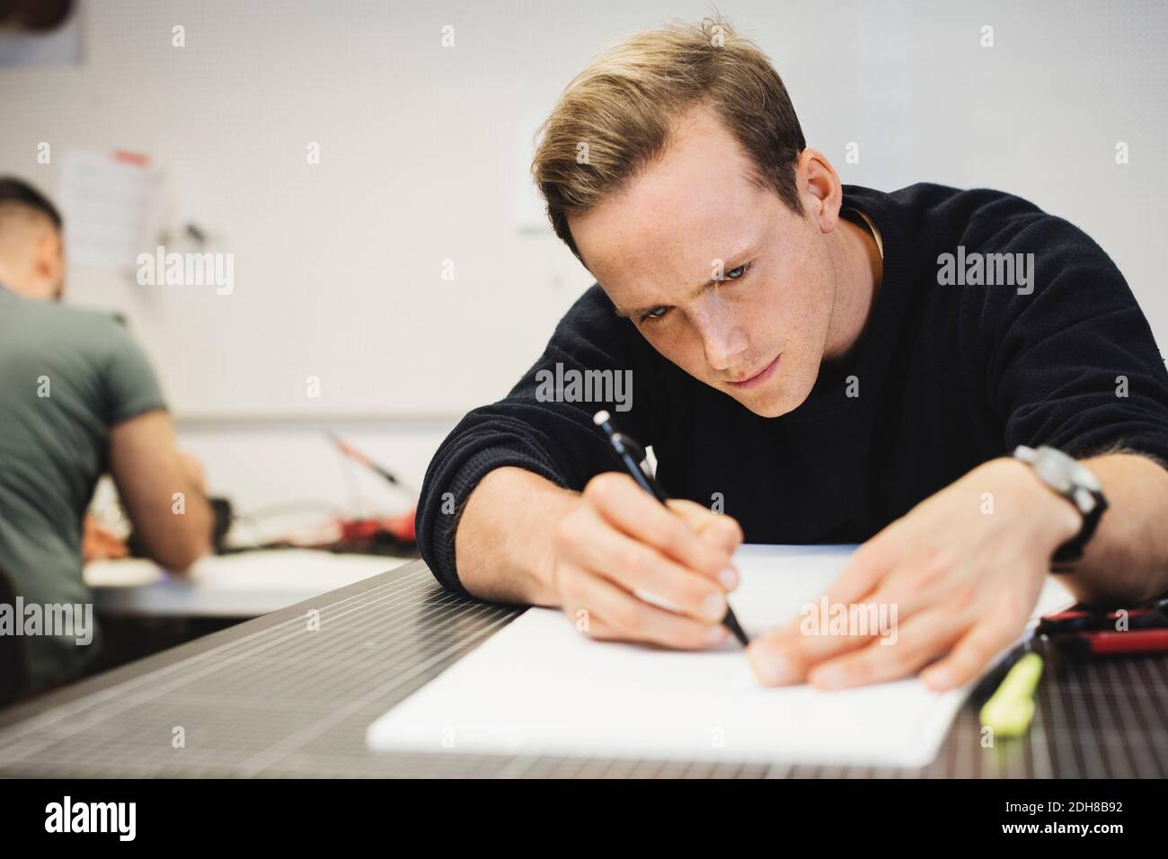 Engineer planning on paper at table with colleague in background Stock Photo