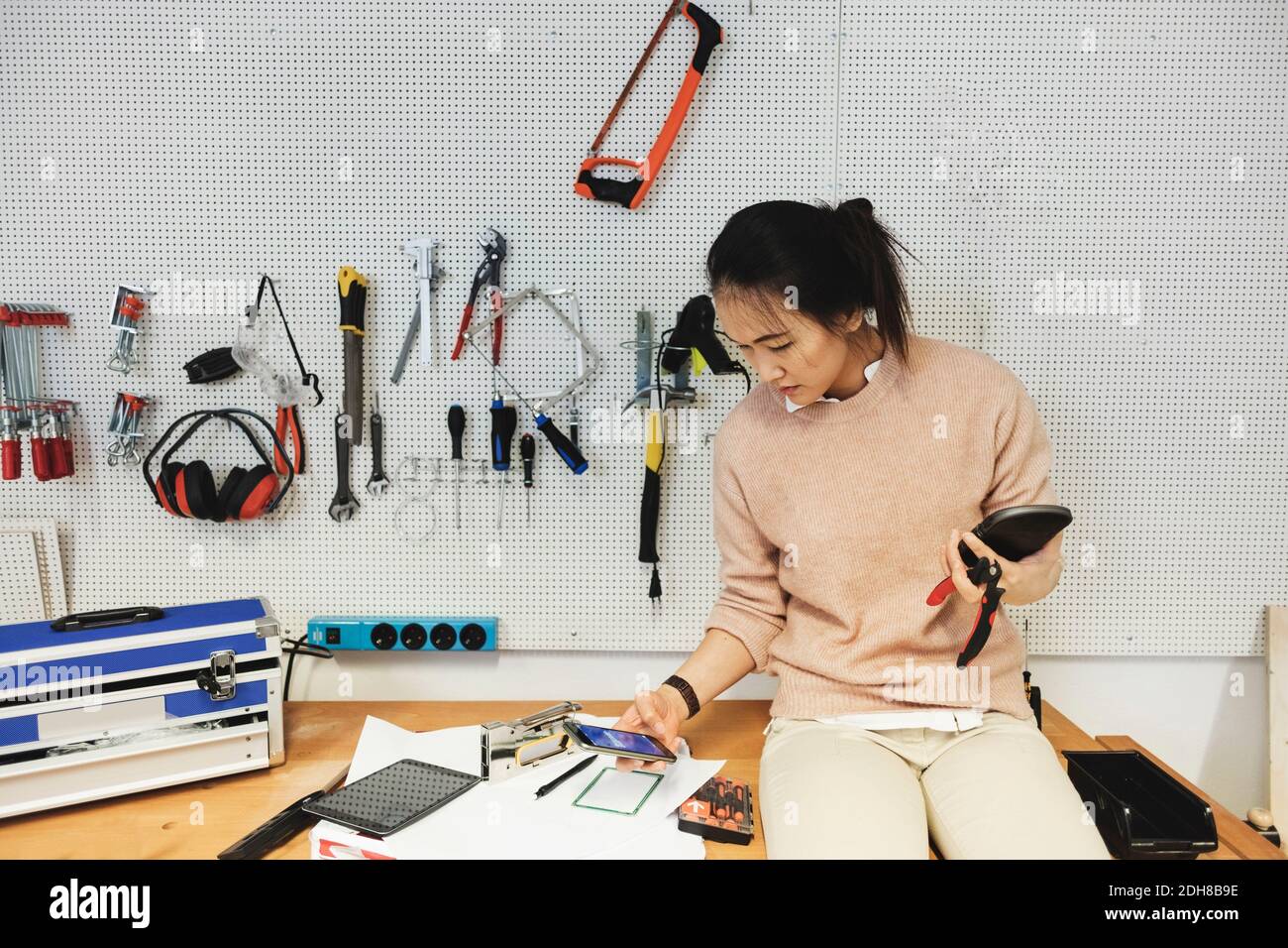 Businesswoman using smart phone while working in workshop Stock Photo