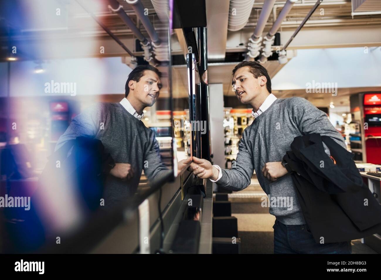 Young man shopping for television in electronics store Stock Photo