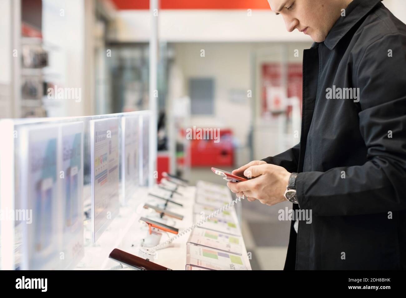 Midsection of young man using smart phone at store Stock Photo