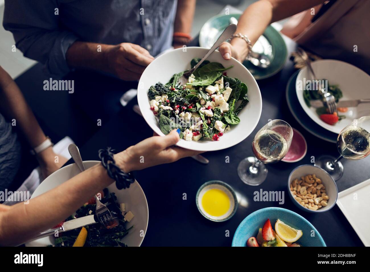 Cropped image of friends holding salad bowl at table Stock Photo