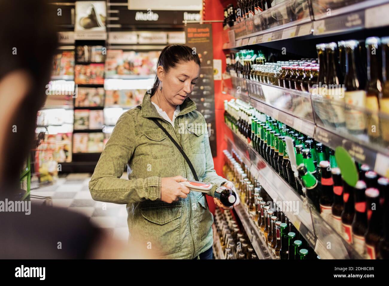 Woman using bar code reader on beer bottle at supermarket Stock Photo