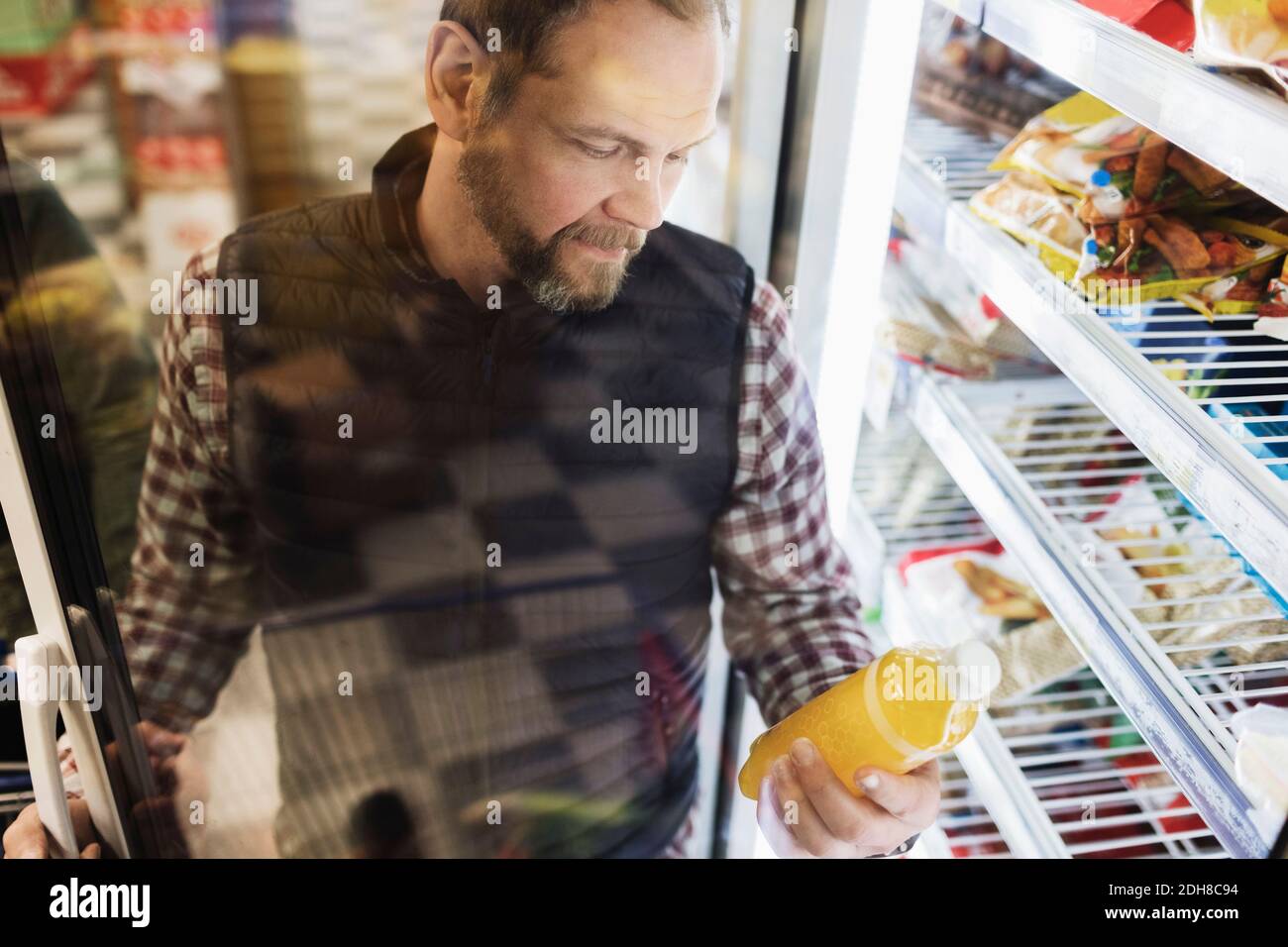 High angle view of male customer reading drink label at refrigerated section Stock Photo