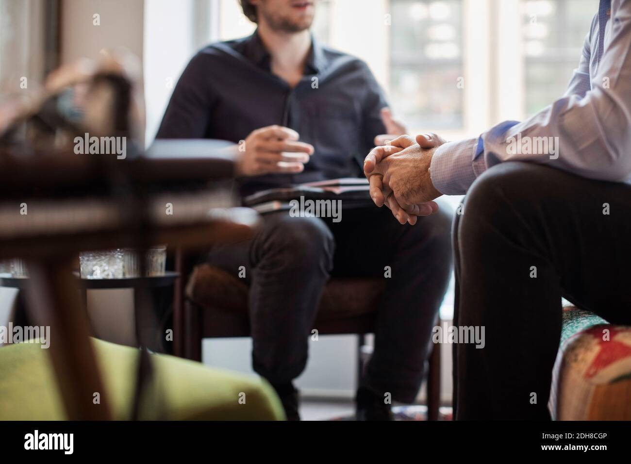 Midsection of businessmen discussing while sitting in office Stock Photo