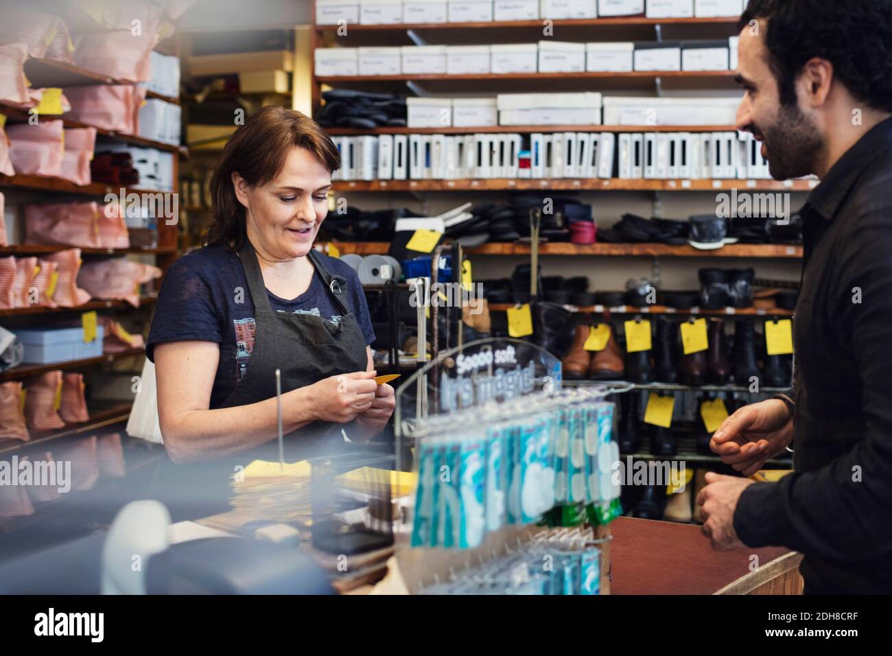 Smiling customer looking at shoemaker reading name tag in shop Stock