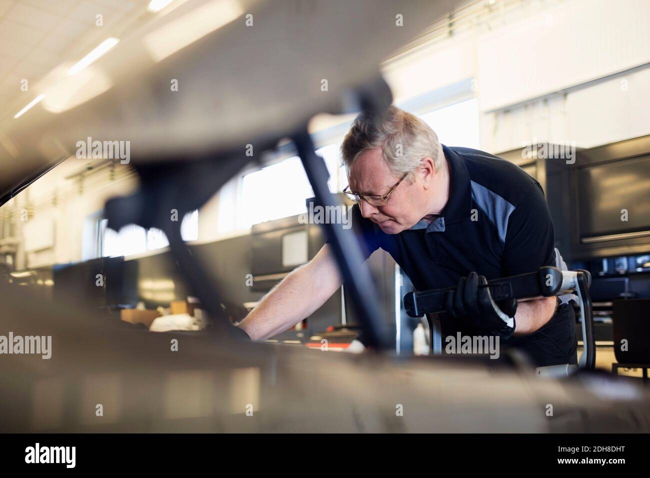 Senior mechanic holding technology while examining car Stock Photo - Alamy