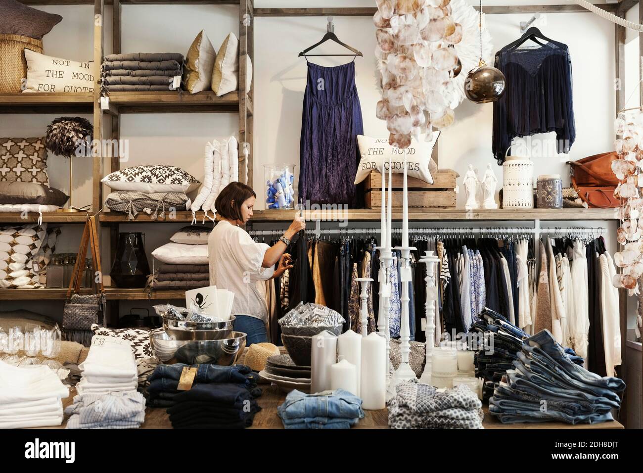 Female owner standing by clothes rack at store Stock Photo - Alamy