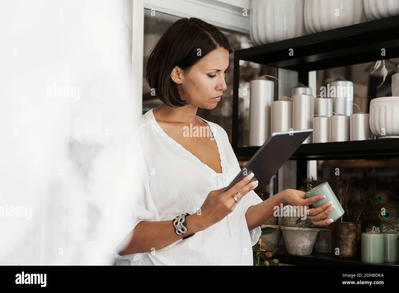 Serious owner checking candle while using digital tablet at store Stock Photo