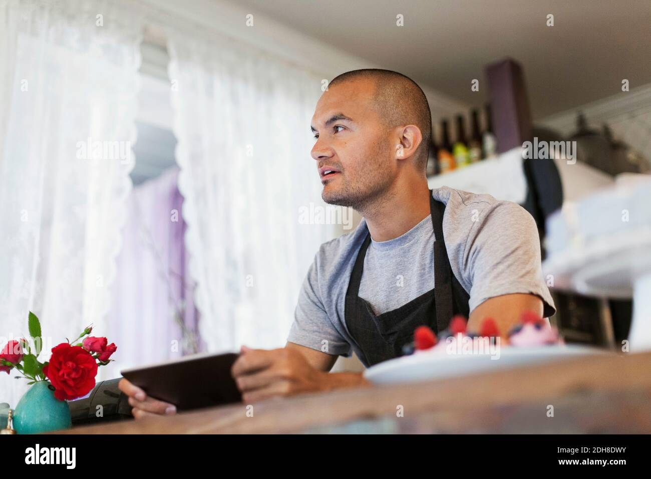 Male owner using digital tablet at cafe counter Stock Photo