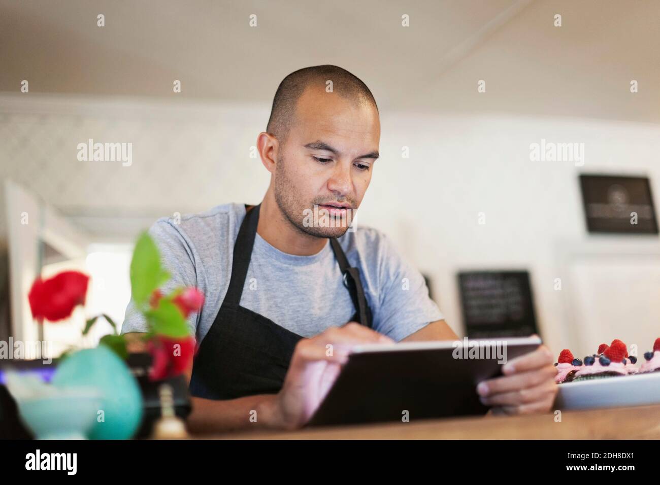 Male owner using digital tablet at cafe counter Stock Photo
