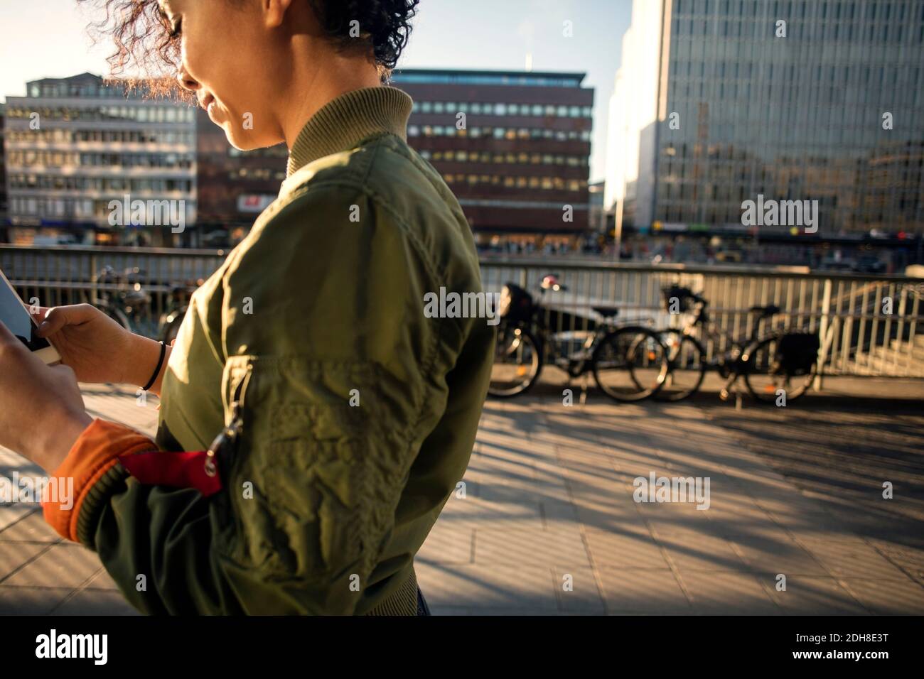 Midsection of teenage girl using phone by street and buildings in city Stock Photo