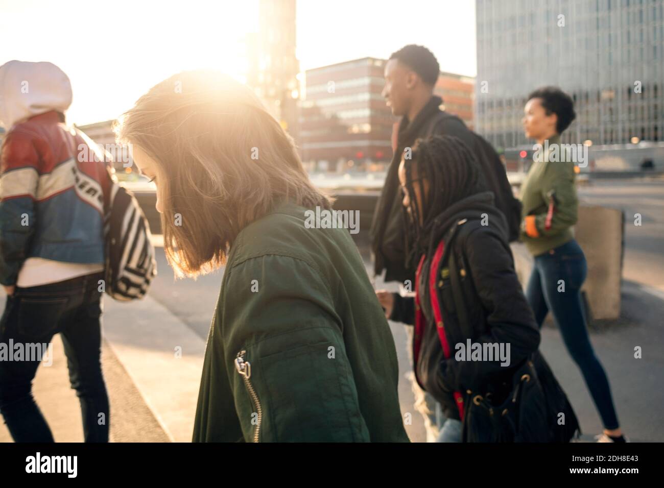 Side view of teenagers walking on street against buildings in city Stock Photo