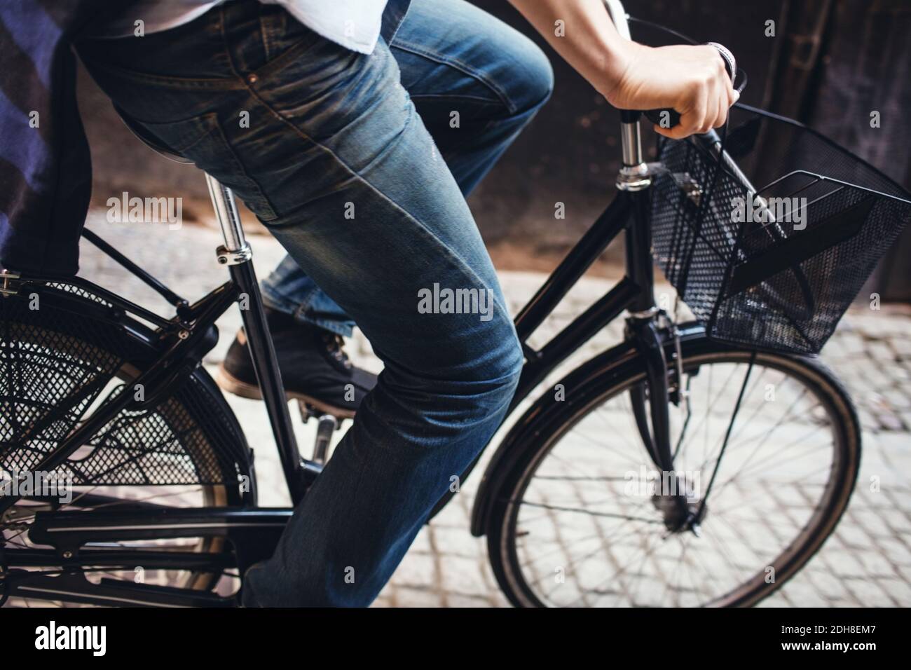 Midsection of man cycling on cobbled street Stock Photo